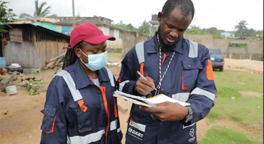 Menxons field team in safety gear reviewing exploration documents on site in Ghana