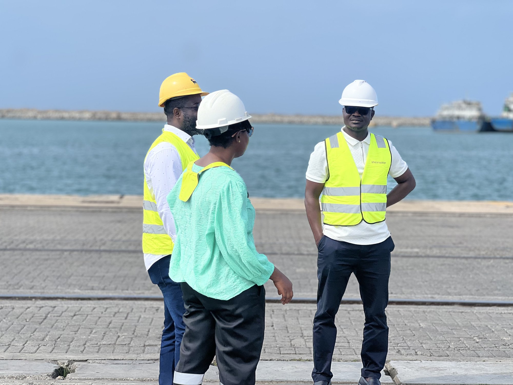 Project team members in hard hats and high-visibility vests in discussion at the quayside in Ghana