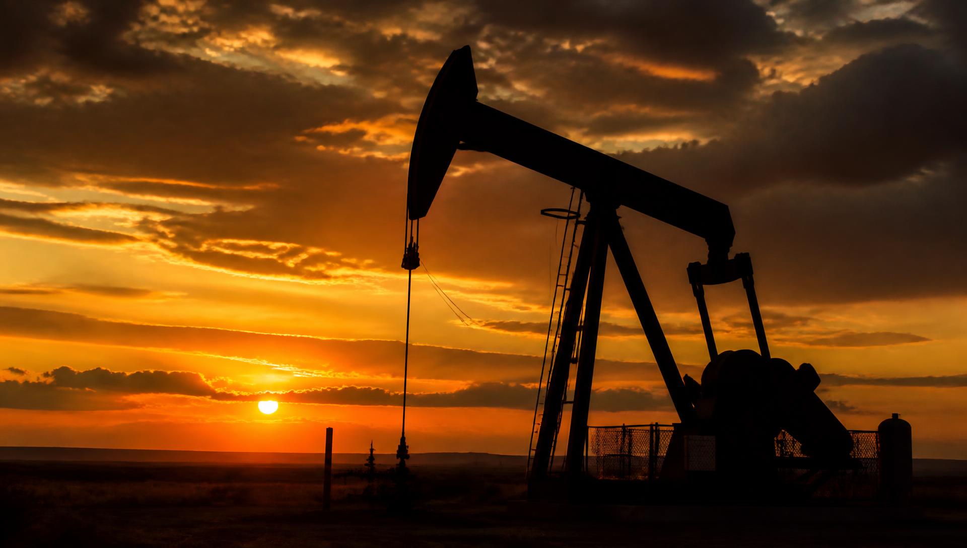 Large pump jack silhouetted against a sunset sky